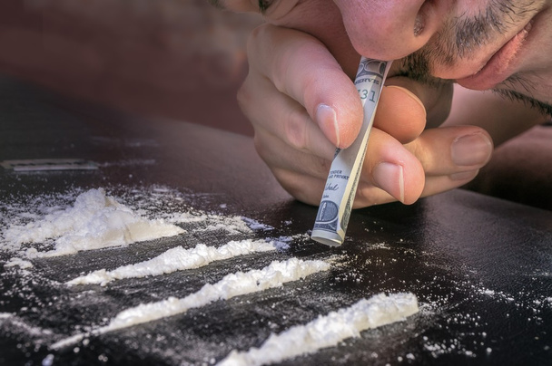 Junkie schnaubt Kokainpulver mit gerollten Geldscheinen. Betäubungsmittelkonzept. - Foto, Bild