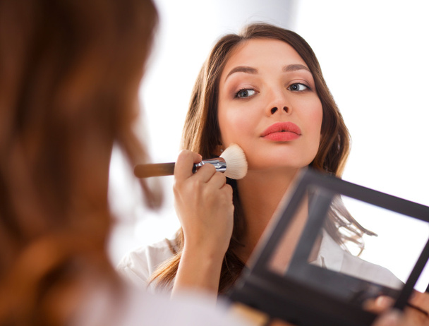 Young beautiful woman making make-up near mirror - Foto, Imagen