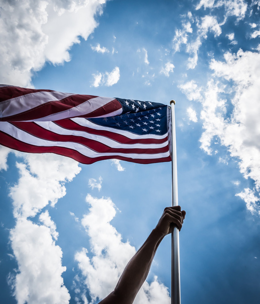 amerikanische Flagge mit Sternen und Streifen mit Händen gegen blu halten - Foto, Bild