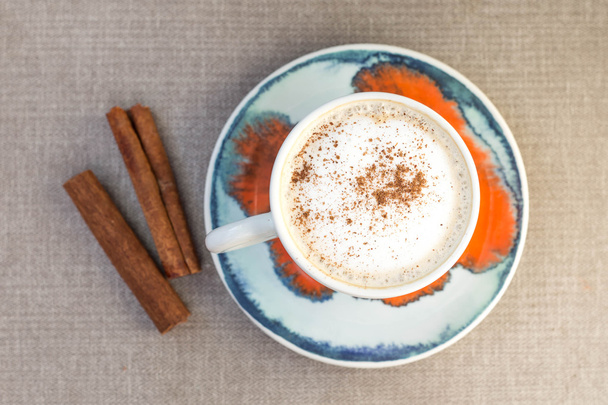 Cappuccino with cinnamon sticks on a table, top view. - Foto, imagen