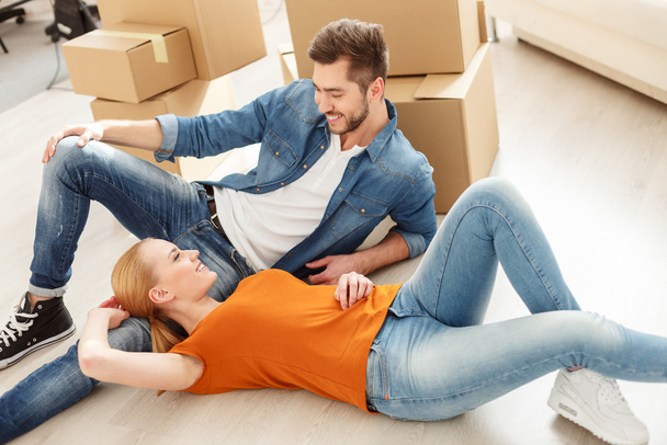 Cute couple lying on the floor in their new home - Photo, image