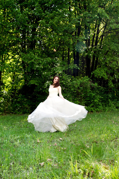 Mooie en gelukkige bruid draaide in een bos-glade - Foto, afbeelding