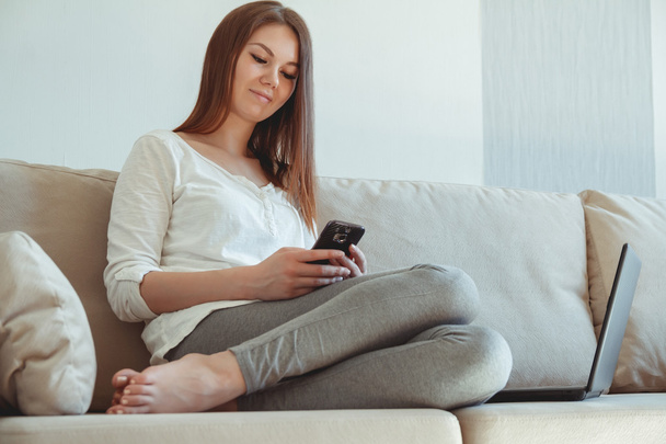 Young girl sitting on the couch with a laptop - Foto, Imagem