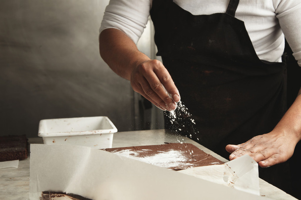Man pours sugar powder on cakes - Valokuva, kuva