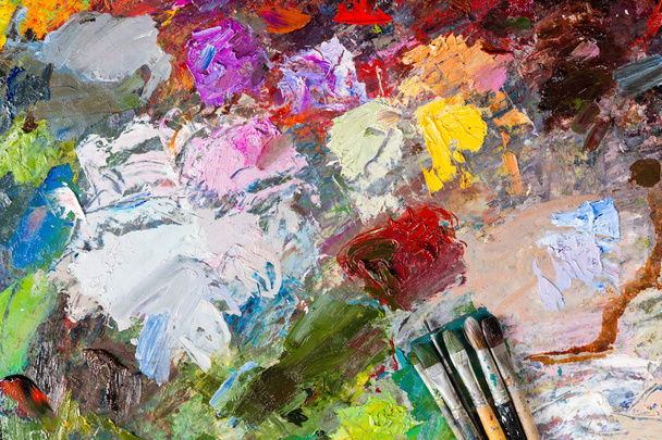 Multicolored palette with paintbrushes - Фото, изображение