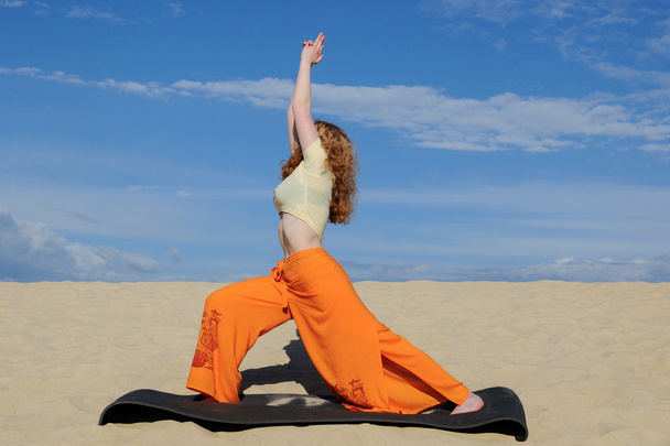 junge rothaarige Frau praktiziert Kriegerpose aus Yoga auf der Ba - Foto, Bild