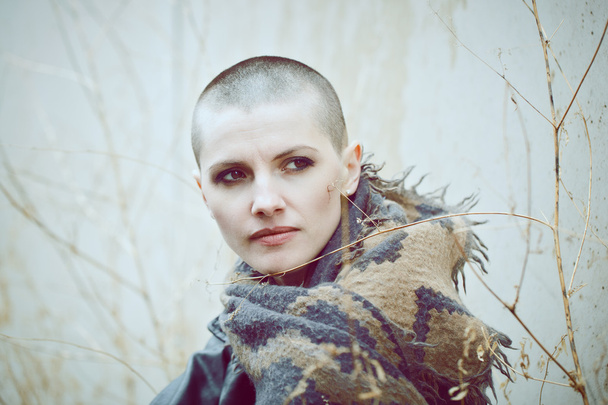 Portrait of sad beautiful Caucasian white young bald girl woman with shaved hair head in leather jacket and scarf shaw looking away, toned with Instagram filters in blue green color - Photo, Image