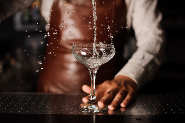 Barman pouring into champagne glass and making a splash - Φωτογραφία, εικόνα