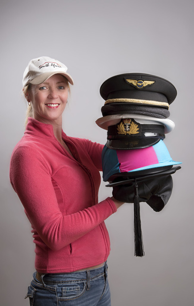 Mujer sosteniendo una variedad de sombreros y gorras de varias profesiones
 - Foto, imagen