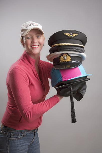 Γυναίκα που κρατά μια ποικιλία από καπέλα και τα καλύμματα από διάφορα επαγγέλματα - Φωτογραφία, εικόνα