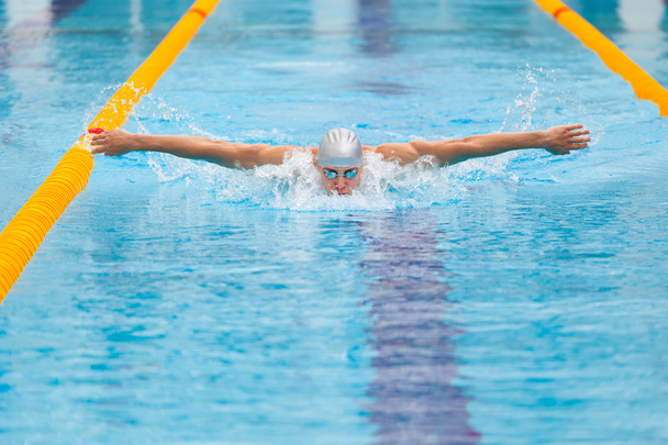 dynamic and fit swimmer in cap breathing performing the butterfly stroke - Фото, зображення