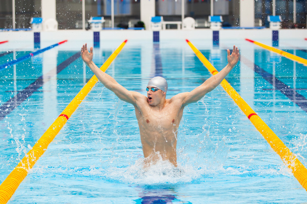 dynamic and fit swimmer in cap breathing performing jumping out the water, concept of victory, freedom, happiness, healthy lifestyle - Фото, зображення
