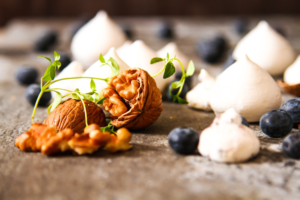 meringue pavlova cake with fresh blueberries and walnuts on dark - Fotó, kép