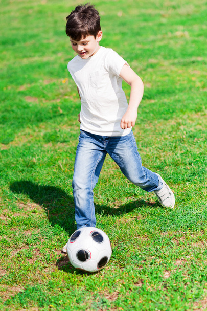 Pretty male child playing football on grass - Photo, image