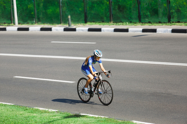 Женщина-велосипедистка едет на гоночном велосипеде по дороге
 - Фото, изображение