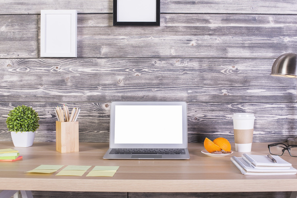 Closeup of modern designer workplace with blank white laptop, stationery items, orange slices, coffee cup, picture frames above and other objects. Mock up - Zdjęcie, obraz