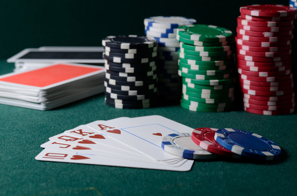 Fichas de casino e combinação de cartas royal flush na mesa verde. Tema do jogo de poker
 - Foto, Imagem