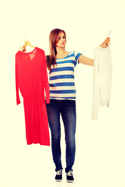 Teenage woman with two shirts thinking what to dress - Foto, afbeelding