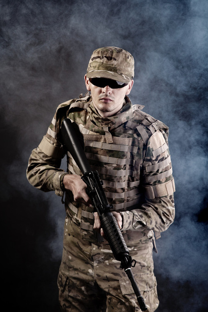 Soldier with a rifle on a black background - Фото, изображение