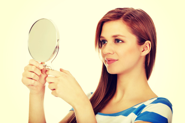 Teenage beautiful woman looking in a mirror - Фото, изображение