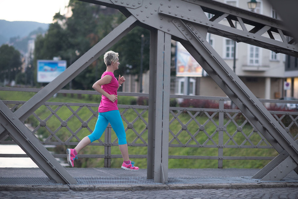 sporty woman running  on sidewalk - 写真・画像