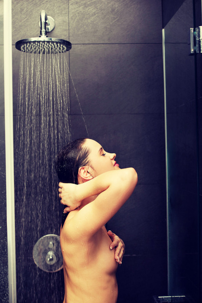 Woman standing at the shower. - Фото, изображение