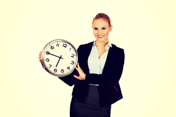 Smiling young business woman holding office clock - Foto, Bild