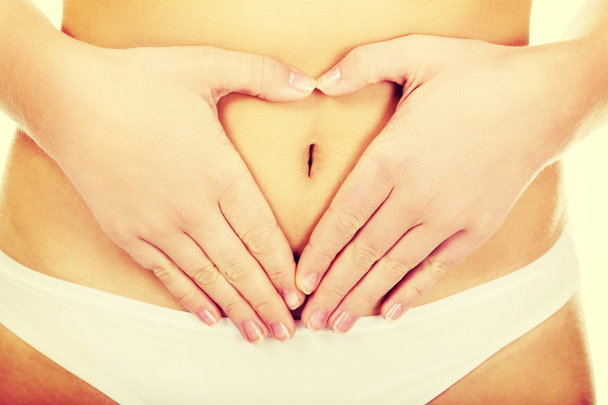 Jeune femme en culotte blanche faisant forme de coeur sur son ventre - Photo, image