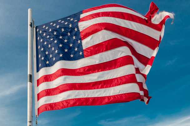 Американский флаг против яркого голубого неба - Фото, изображение