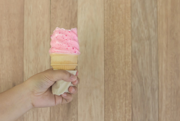 Cône de fraise crème glacée tenue jusqu'à l'été chaud sur le dos de bois
 - Photo, image