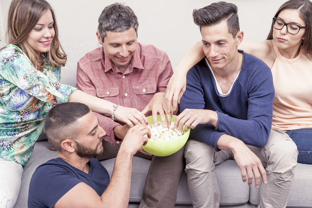 ryhmä ystäviä syö popcornia sohvalla
 - Valokuva, kuva