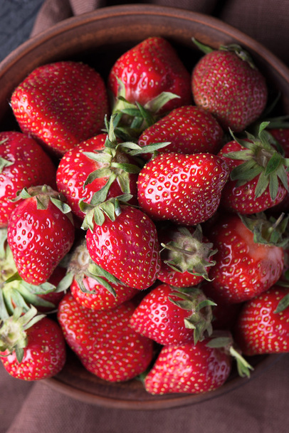 frische Erdbeere in der braunen Schüssel auf dunklem Tisch - Foto, Bild
