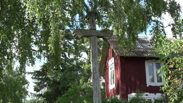 Cruz de madera retro entre ramas de abedul en movimiento cerca de la casa rural. 4K
 - Metraje, vídeo