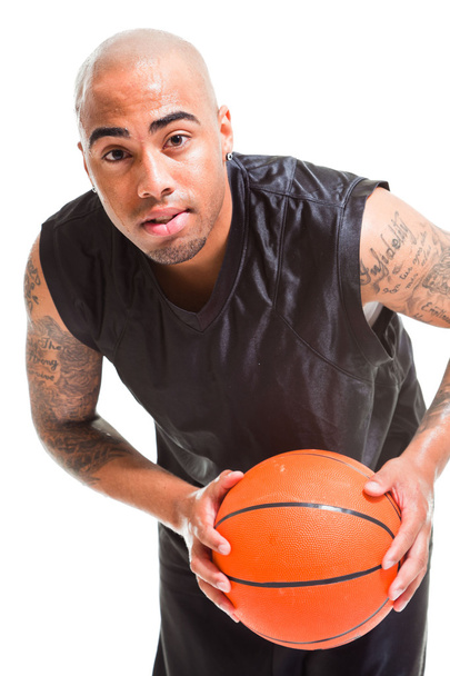 Studio portrait of basketball player standing and holding ball isolated on white. Tattoos on his arms. - 写真・画像