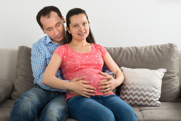 W ciąży para siedzi na kanapie - Zdjęcie, obraz