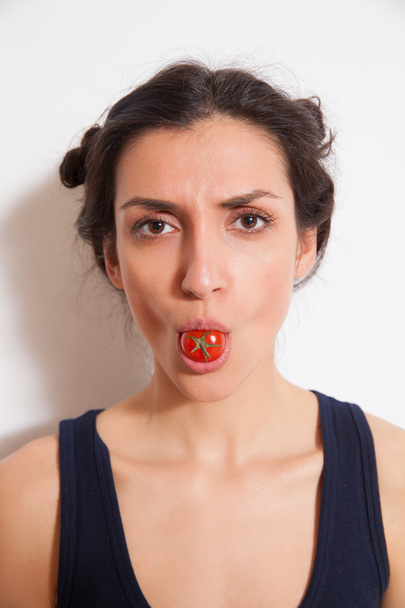 Jovem segurando tomate cereja nos lábios
 - Foto, Imagem