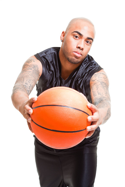 Портрет молодого баскетболіста, що стоїть з м'ячем на білому тлі. Студійний знімок. Татуювання на руках
. - Фото, зображення