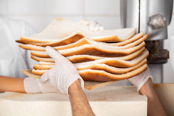 Bakers Hands Passing Unwanted Bread Slices - 写真・画像