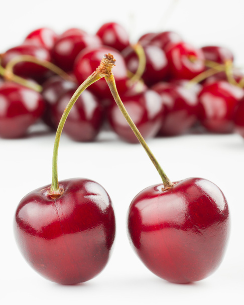 Two red cherries and pile of cherry as background - Fotografie, Obrázek