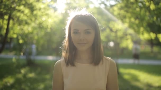 Surprisingly beautiful woman in a light blouse on background of summer park - Materiaali, video