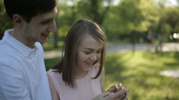The guy with the girl looking at the phone and smiling - Imágenes, Vídeo