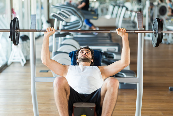 Man lifting weight in fitness club - Fotó, kép
