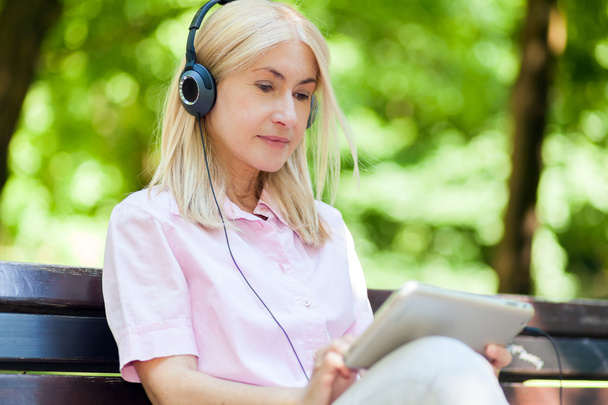 mature woman listening music outdoors - Foto, Imagen