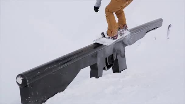 Snowboarder salto en el sendero de hierro en la montaña nevada. Trucos. Concurso. Desafío. Extremadamente. Estación de esquí
 - Metraje, vídeo