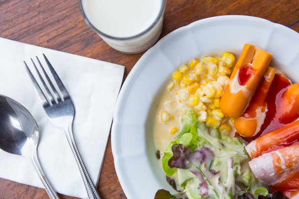 Ранковий овочевий салат з хот-дог на тарілці та молоці
 - Фото, зображення