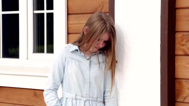 Videoporträt eines jungen glücklich lächelnden Mädchens auf dem Hintergrund ihres Hauses - Filmmaterial, Video