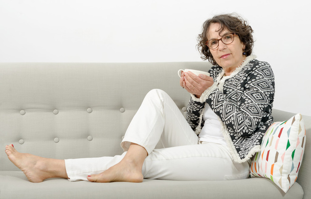 érett nő teázás a kanapén - Fotó, kép