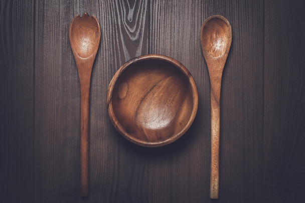 wooden salad bowl and two spoons on the brown table - Φωτογραφία, εικόνα