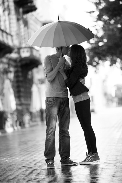 傘が付いている都市の路上で若いカップル - 写真・画像