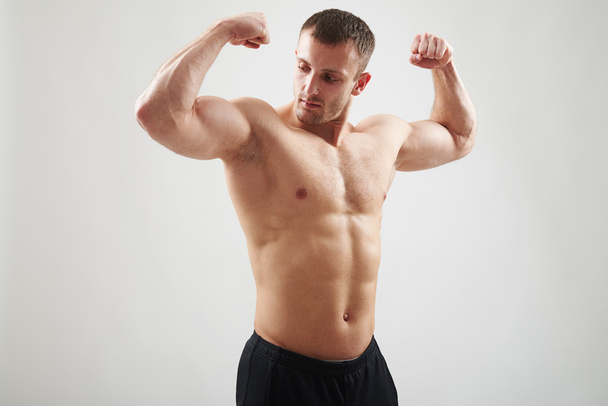 Muž s obnaženými prsa zobrazující svaly izolované na bílém pozadí - Fotografie, Obrázek